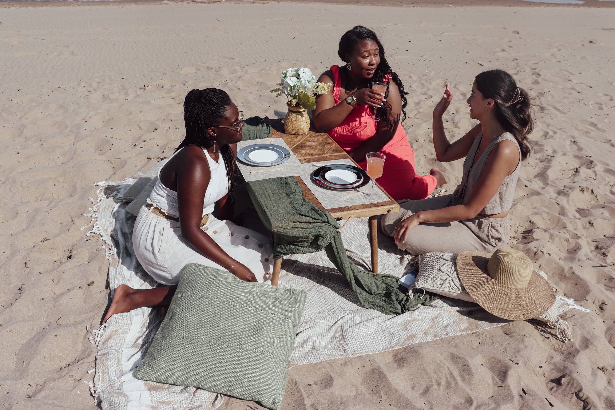 Three friends around a styled low picnic table on the beach in Grand Bend